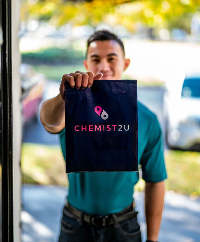 A courier delivering a Chemist2U-branded bag containing medications to a customer.