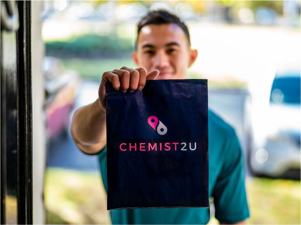 Chemist2U delivery courier handing over a medication delivery bag at the door